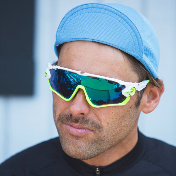 Man wearing sunglasses and a Blue 4-panel cap with brim up.