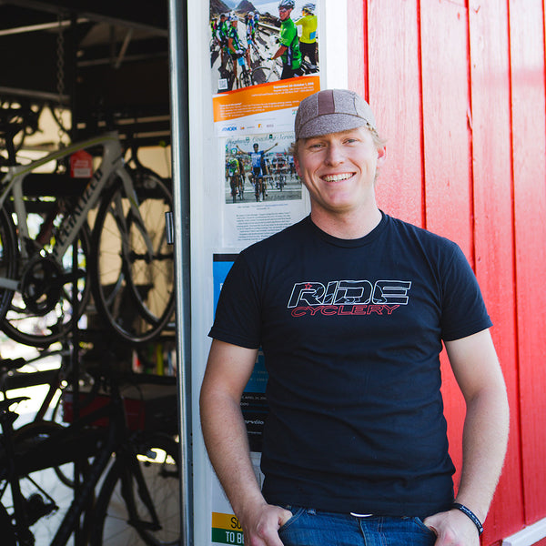 Man wearing brown twee cap in front of bike shop.